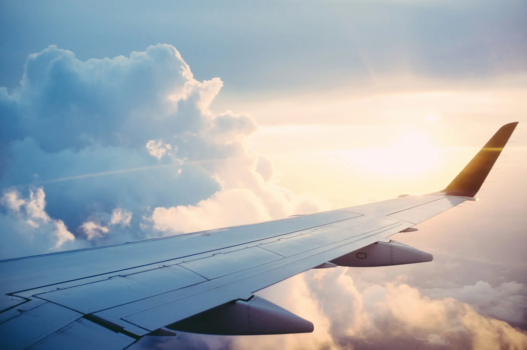 View over an aircraft wing above the clouds at sunset